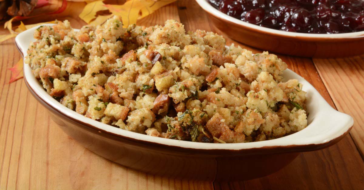 A dish of turkey stuffing placed on a wood table.